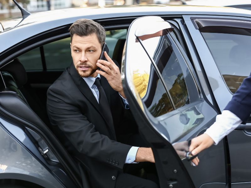 Professional man in a suit exiting a luxury car with Blaine MN car service assistance.