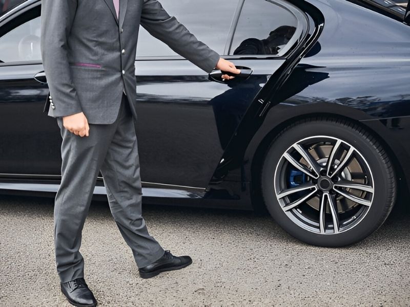 Professional chauffeur opening door for luxury car service in Shorewood MN.