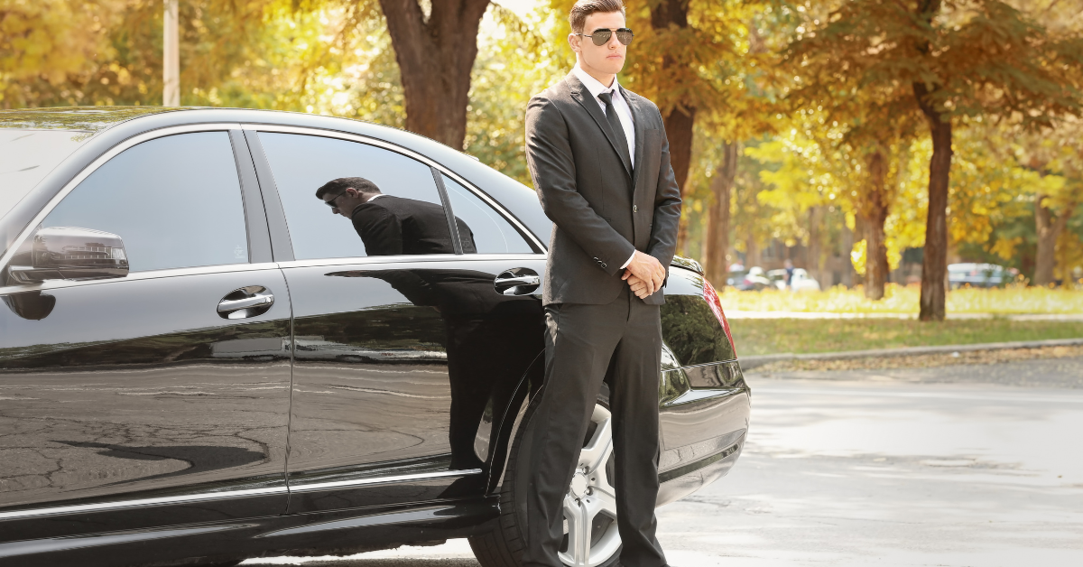 Professional driver standing beside luxury car – Why Use Point-to-Point Transfer in Minneapolis for reliable travel.